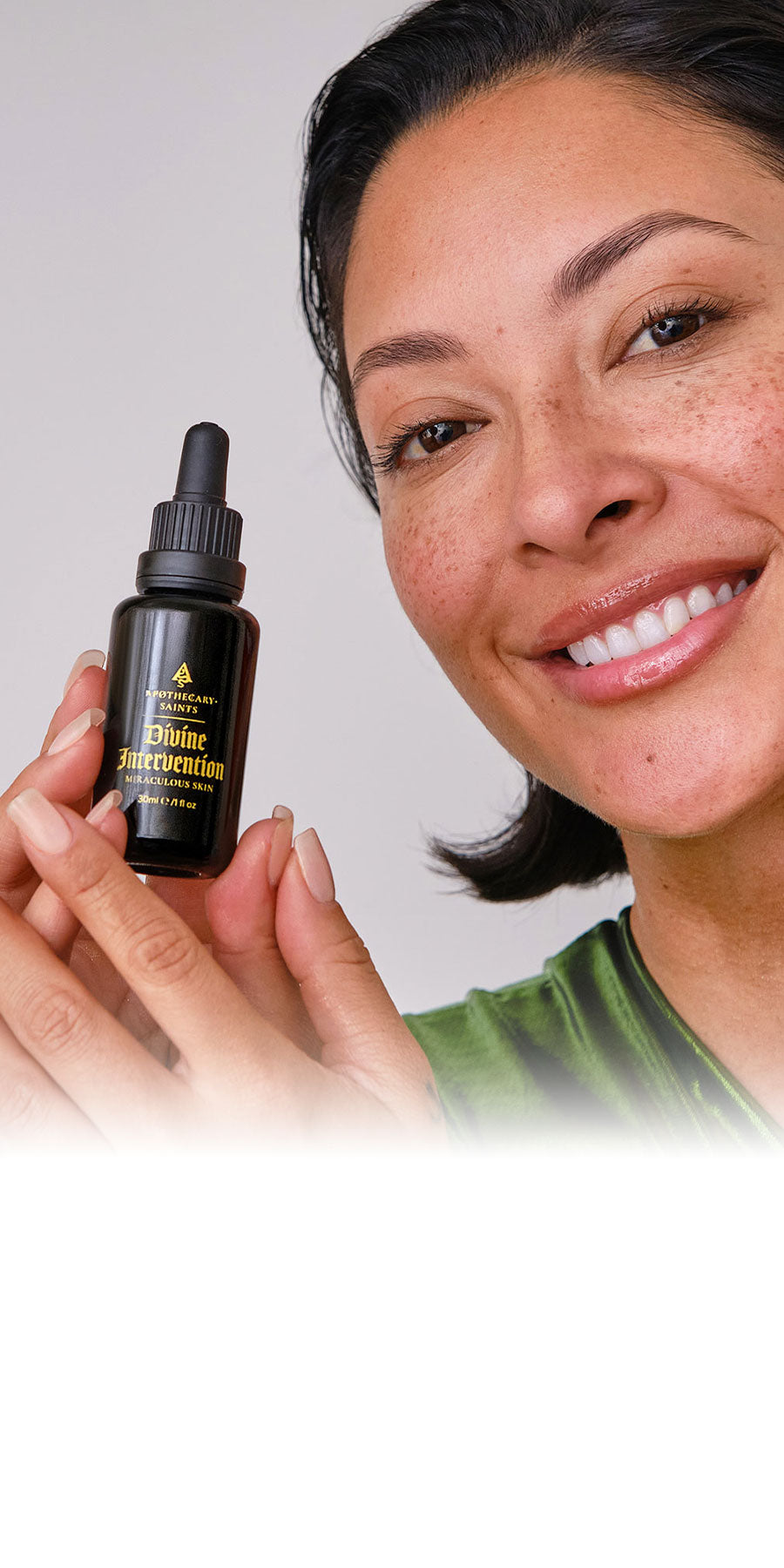 Woman holding a bottle of Divine Intervention face oil with a neutral background