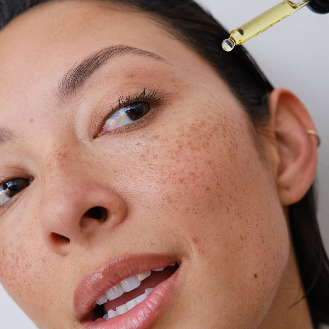 Close-up of woman applying face oil to her face