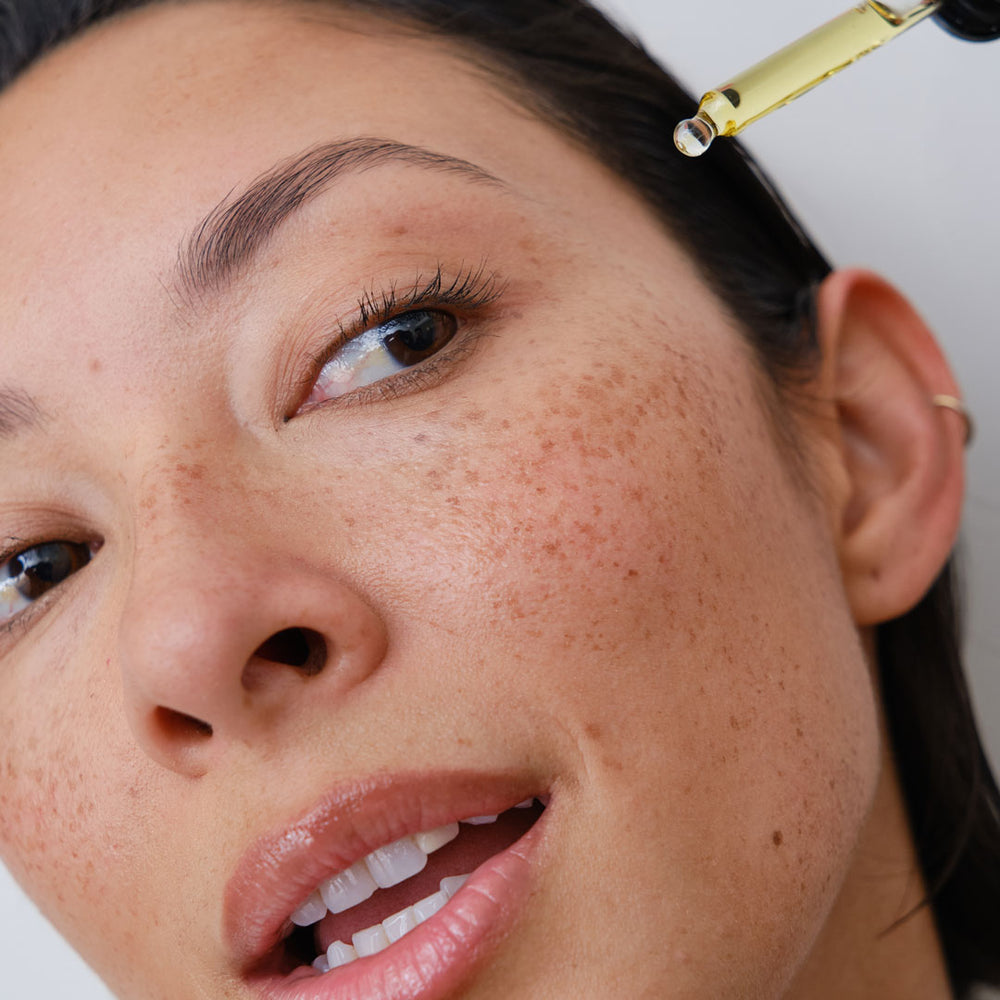 Close-up of woman applying face oil to her face