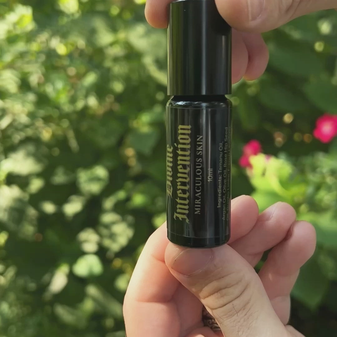 hand applying divine intervention face oil from roller bottle